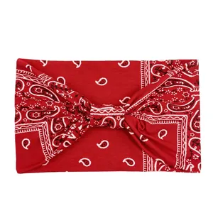 Close-up of red paisley bandana headband with twist knot detail on white background