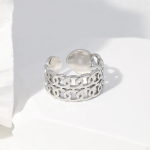 Detailed close-up of silver double-chain stainless steel open ring on a white stone base