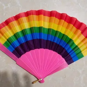 Rainbow folding fan with pink plastic frame displayed on a marble surface background