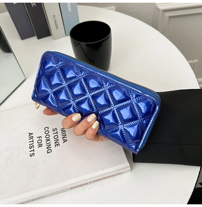 Close-up of vibrant blue quilted patent leather clutch purse with golden zipper