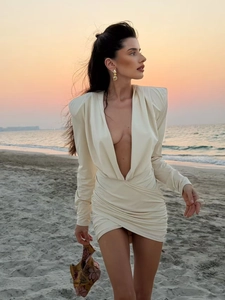 Detail of elegant white long-sleeve dress with deep V-neck and ruched waist details