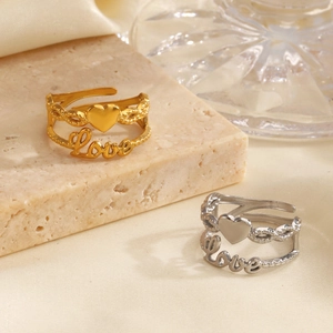 Golden and silver stainless steel rings with heart and Love design on stone background