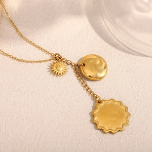 Close-up of gold 18K plated necklace featuring sun, round disc, and octagonal star pendants