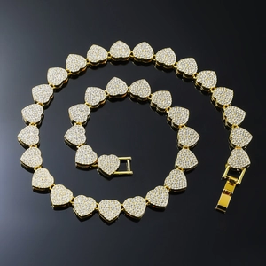 Macro detail of gold-plated heart-shaped Cuban link necklace with sparkling crystals