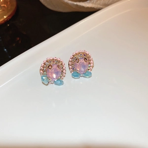 Vue macro de boucles d'oreilles en cristal rose avec pierres bleues et perles dorées