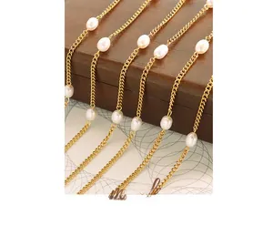 Detailed close-up of 18K gold chain with white freshwater pearls on a wooden jewelry box