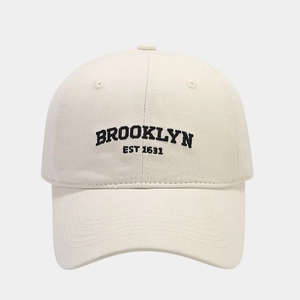 Detailed front view of a cream cotton baseball cap with black Brooklyn embroidery