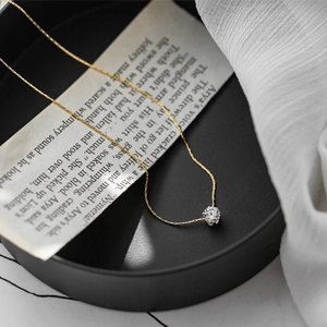 Close-up of minimalist gold thin chain necklace with a sparkling round zircon pendant