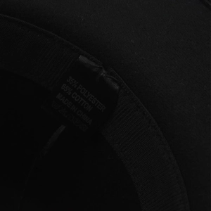 Detail of internal hat label showing 65% cotton 35% polyester material and wash instructions