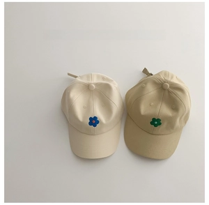 Détail de casquettes enfant beige et kaki avec broderie florale minimaliste