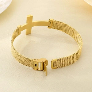 Detail of gold cross charm and milanese mesh texture on stainless steel bracelet