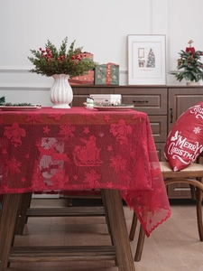 Detailed view of red lace Christmas tablecloth featuring reindeer and Santa Claus motifs