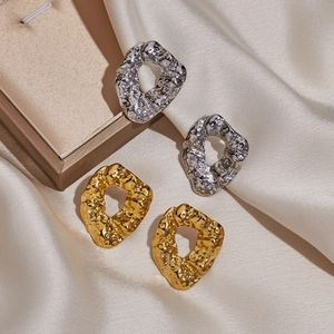 Detail of irregular geometric gold and silver earrings with hammered texture on silk