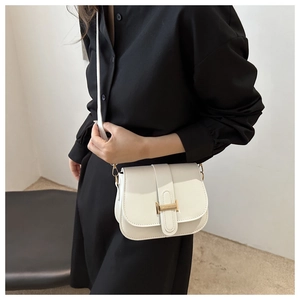 Close-up of a white square shoulder bag with a gold H-shaped buckle on a model