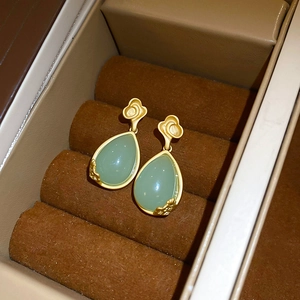 Macro shot of gold teardrop earrings with green jade inlays and cloud patterns