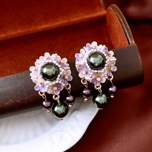 Close-up of vintage tassel earrings with dark pearls and floral beadwork on leather