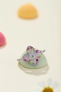 Macro shot of silver four-petal flower ring with colorful cubic zirconia crystals