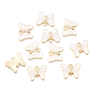 Detailed view of ten white enamel butterfly pendants with golden alloy frames on white backdrop