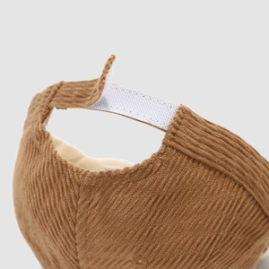 Close-up of the adjustable white velcro strap on the back of a brown corduroy baseball cap