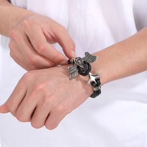 Close-up of leather bracelet with silver skull and anchor charms on wrist