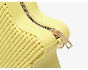 Close-up of yellow PVC bag showing grainy texture surface and golden metal zipper detail