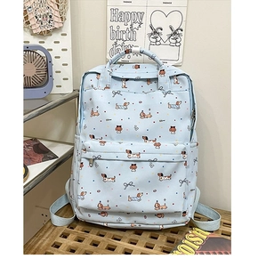 Detail of light blue backpack featuring cute cartoon dog and bow prints with front pocket