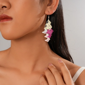Detail of multi-layered butterfly drop earrings featuring yellow, pink and white enamel colors