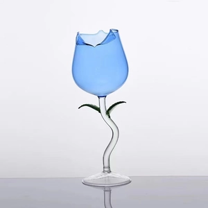 Artistic blue tulip-shaped glass with green leaves and a curved transparent stem