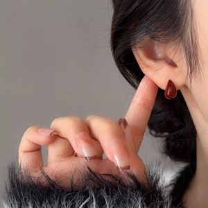 Gros plan de la boucle d'oreille goutte rouge foncé portée par un mannequin