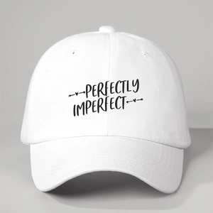 Gros plan sur la broderie noire 'PERFECTLY IMPERFECT' sur une casquette vintage blanche