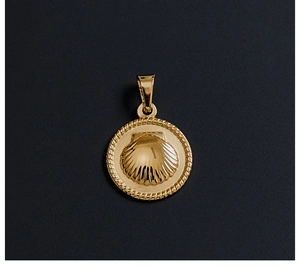 Detail view of a shell-shaped gold pendant with rope border on a dark textured surface