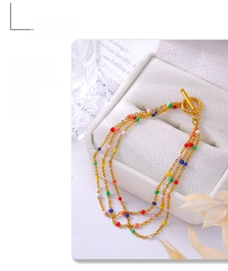 Detailed close-up of a gold-plated multi-layer bracelet with colorful enamel beads and OT clasp