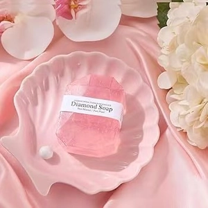 Close-up of diamond-shaped pink handmade soap on a shell tray with silk and flowers