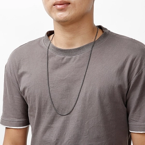Vue détaillée d'un long collier en acier titane sur un mannequin portant un t-shirt gris