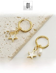 Détail rapproché des boucles d'oreilles en acier titane doré avec étoiles et perles
