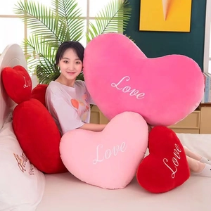 Detail of plush heart-shaped pillows with Love embroidery in cozy bedroom setting
