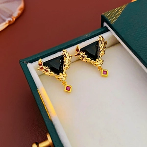 Details von vergoldeten Vintage-Ohrringen mit schwarzem Dreieckstein und rotem Anhänger
