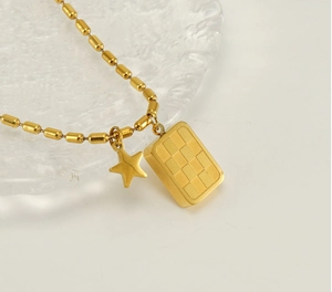 Détail du pendentif carré à damier doré et de la petite étoile sur collier en acier