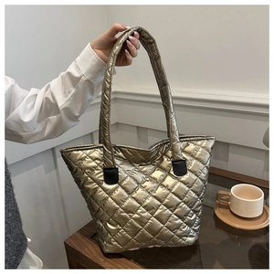 Detail of metallic gold quilted tote bag showing rhombus texture and handle stitching