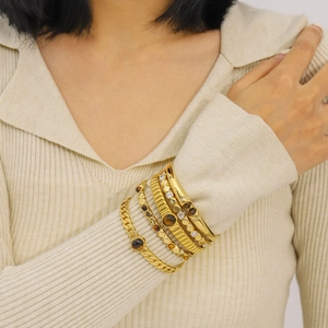 Minimalist gold bangle set with tiger eye stones and zircons on female wrist