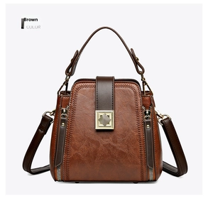 Close-up of brown textured leather bucket bag with gold square buckle and side zippers