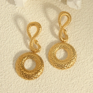 Vintage gold snake texture earrings with drop pendant on a white minimalist background