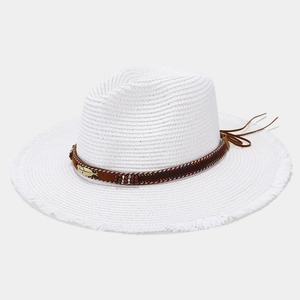 Detailed close-up of white straw sun hat with ethnic brown band and gold feather charm