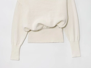 Detail of soft ivory knit fabric showing ribbed cuffs and hem on an off-shoulder sweater