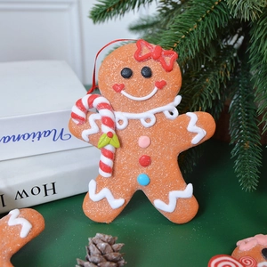 Gingerbread man Christmas tree ornament with red bow and candy cane on festive branches