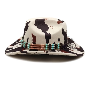 Western cowboy hat with cow print pattern and ethnic beaded band on white background