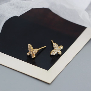 Close-up of golden butterfly stud earrings inlaid with clear sparkling cubic zirconia