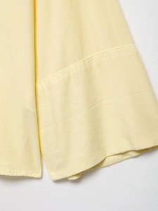 Macro detail of high-quality linen blend fabric texture and stitching on yellow sleeve hem