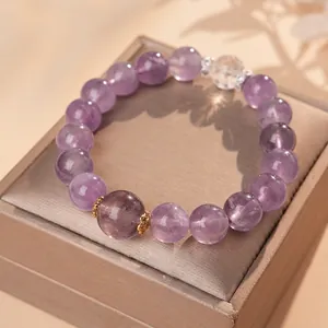 Elegant amethyst beaded bracelet with gold accents and zircon rings on silk display