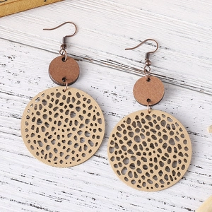 Detailed macro shot of vintage geometric drop earrings with wood and hollow leather texture
